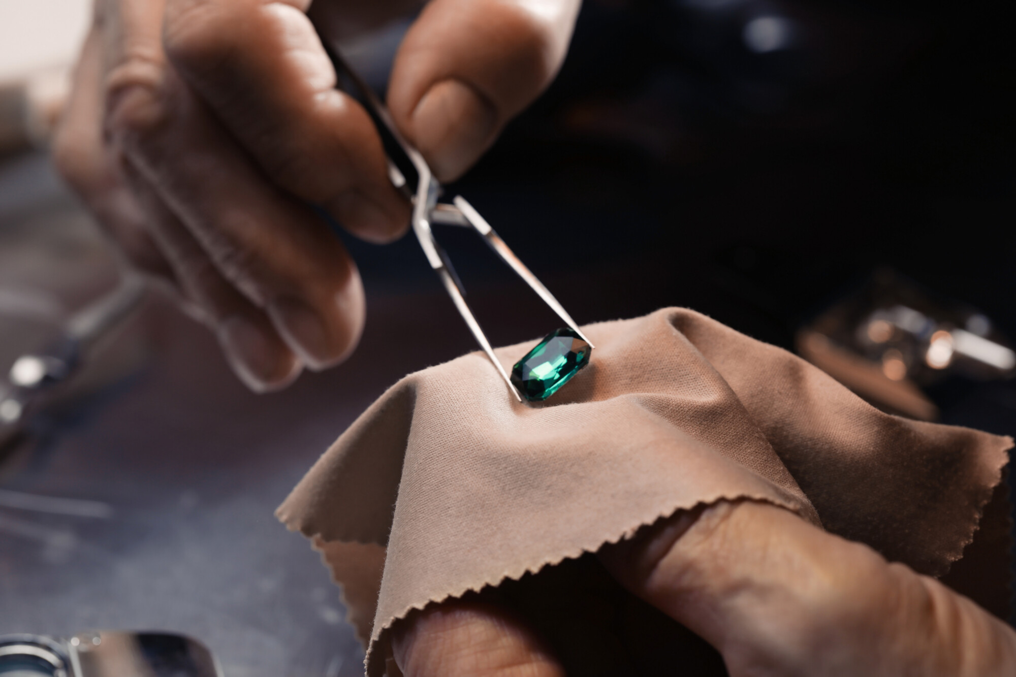 A close look at a gemstone held in a jeweller’s tweezers