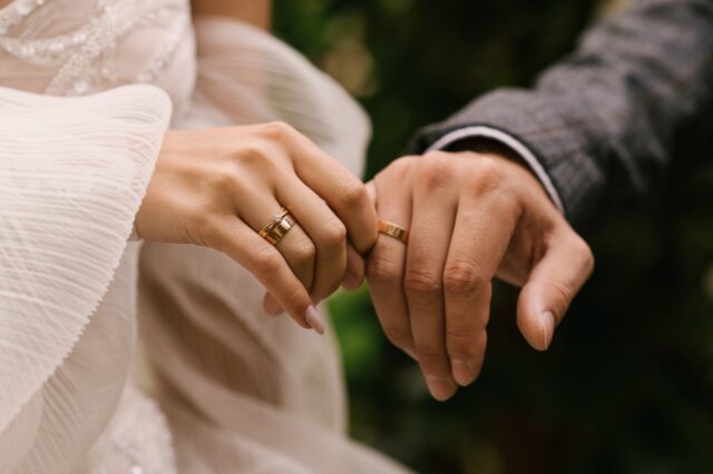 Matching vs complementary wedding rings worn by a couple and explored with Kinzy London