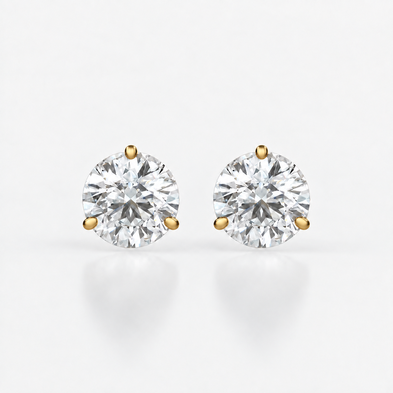 Front view of three-claw martini round diamond stud earrings in yellow gold