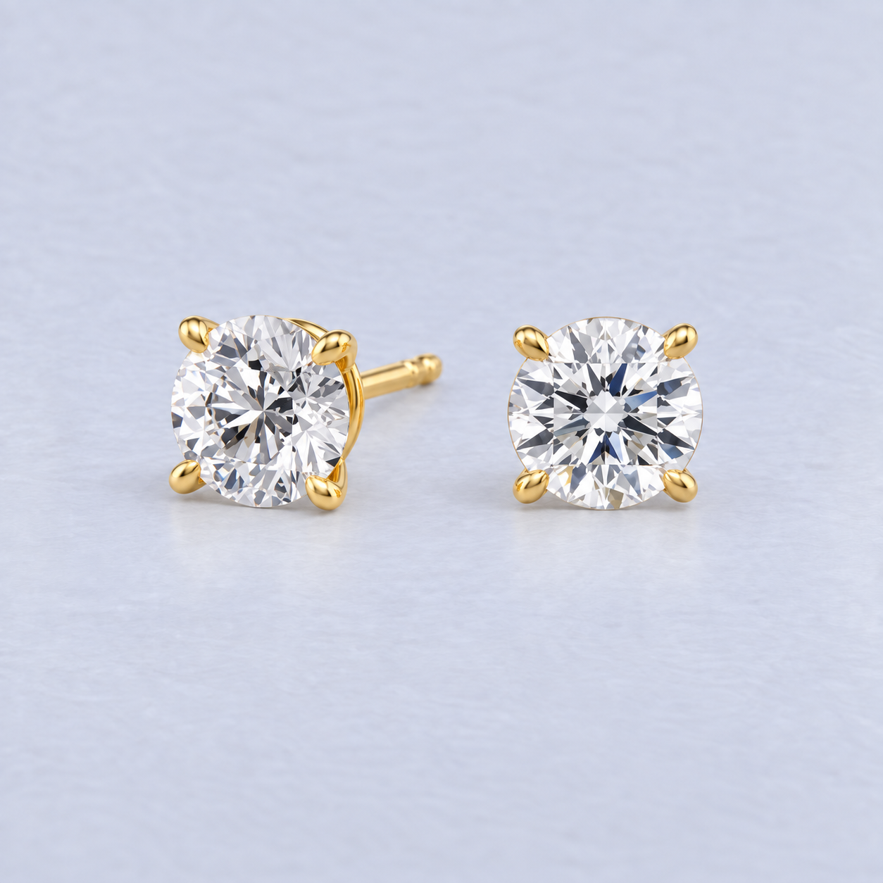 Pair of round diamond stud earrings in yellow gold four-claw settings, main view