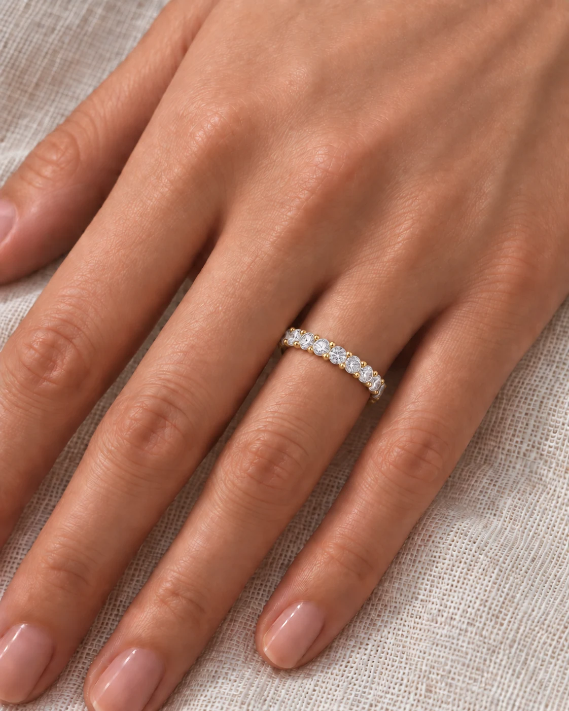 Shared Prong Diamond Eternity Ring in yellow gold worn on the ring finger